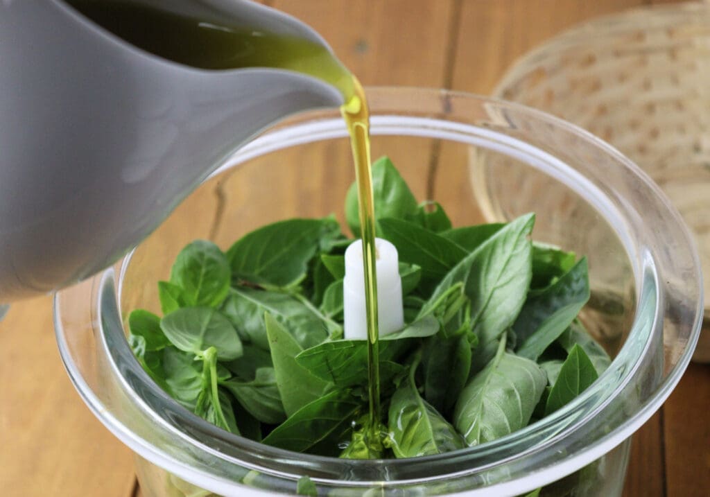 image of blending basil leaves with olive oil in a food processor